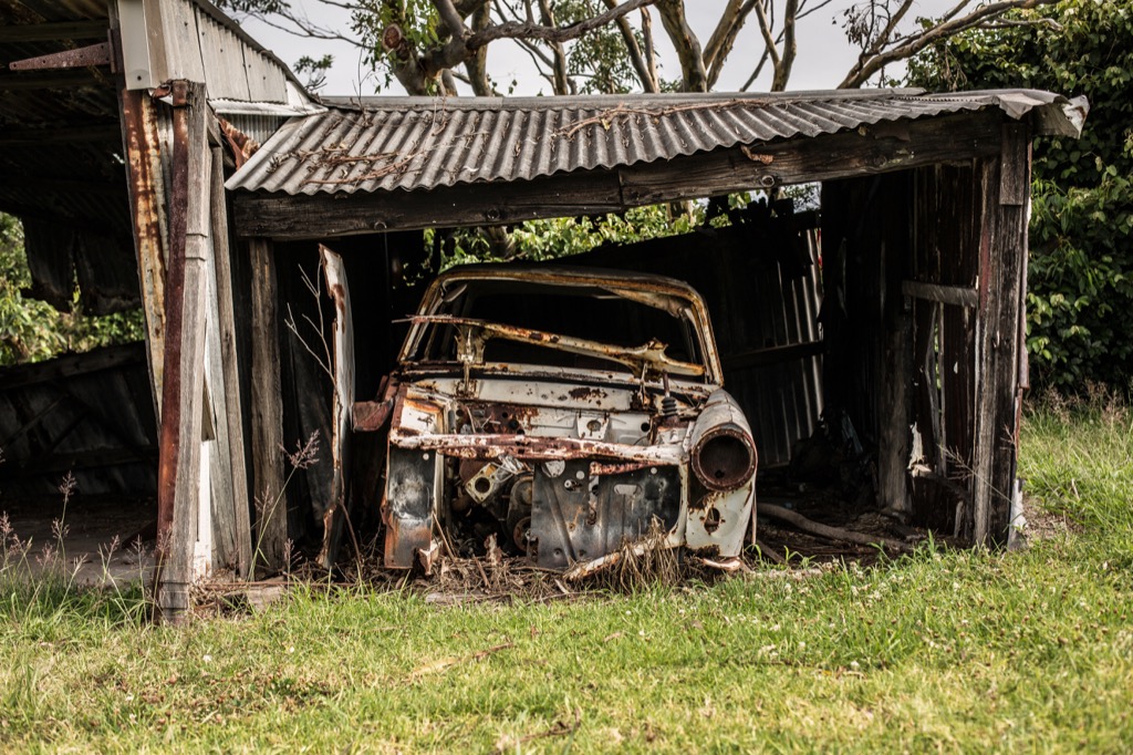 An old car mouldering in a rotting garage