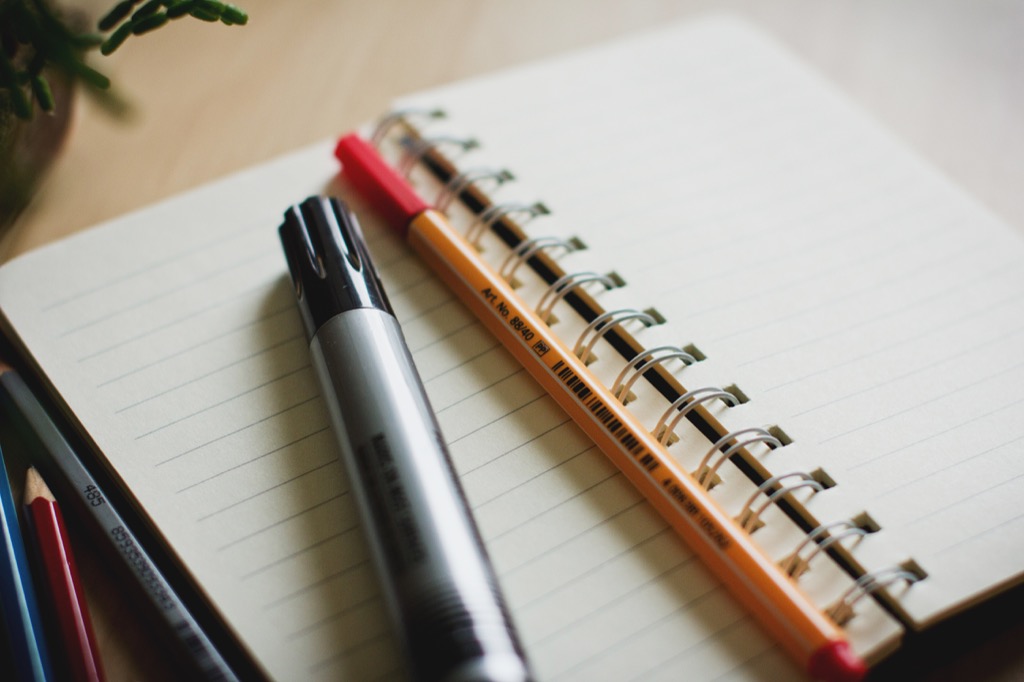 A notebook with a marker and a pen resting on it