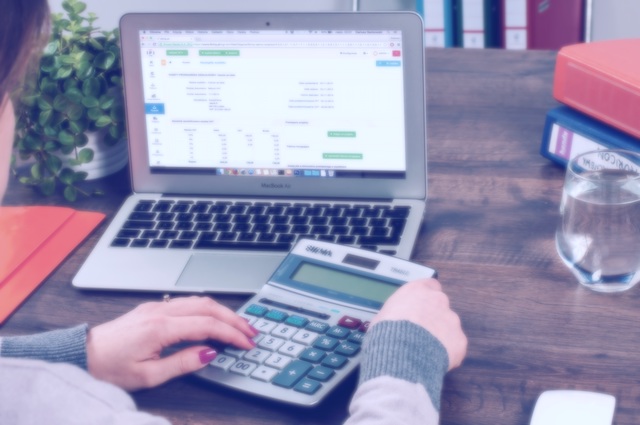 A person using a computer and a calculator at the same time for some insane, stock-photo related reason